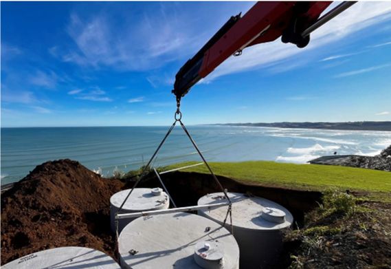 Concrete rainwater tanks being installed by crane at a coastal property